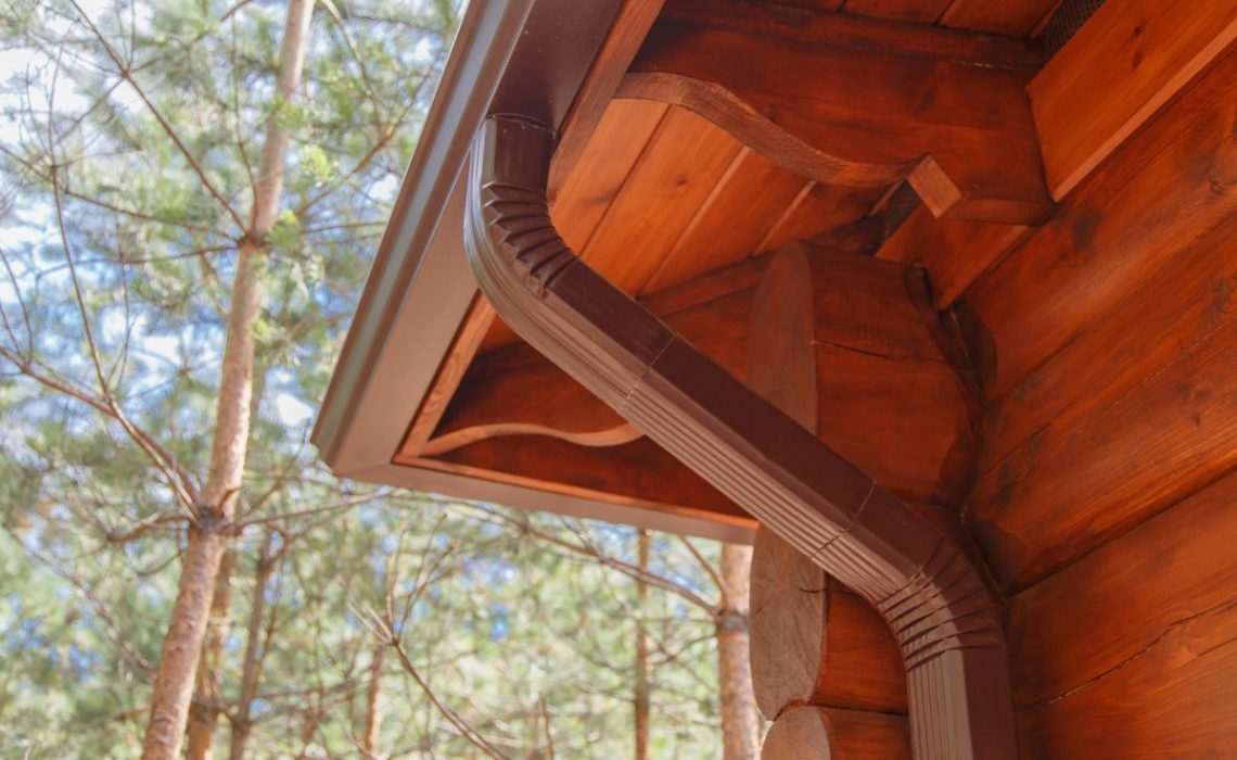 Roof gutter system on log house in forest.