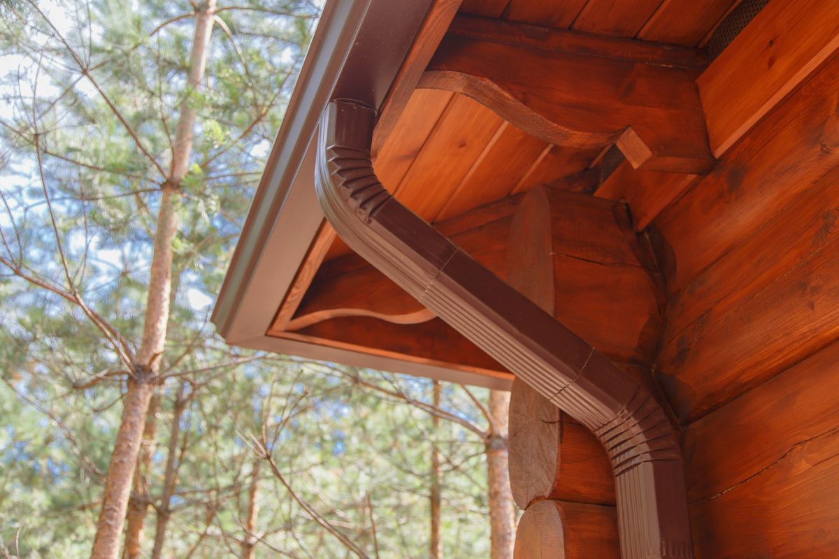 Roof gutter system on log house in forest.