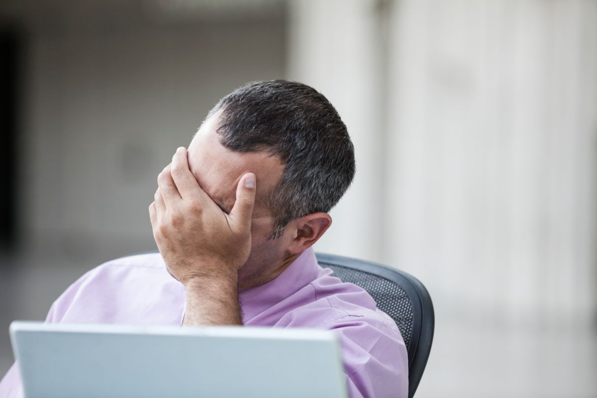 A Caucasian businessman pondering a problem while working on a laptop computer.