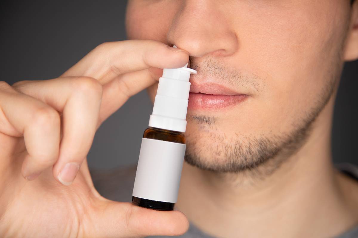 A male use nasal spray and apply the bottle to his nose