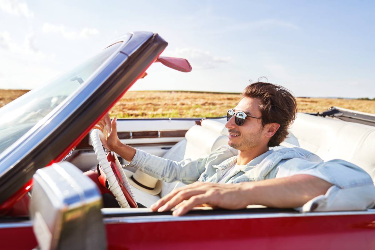 Handsome man with sunglasses driving an old car