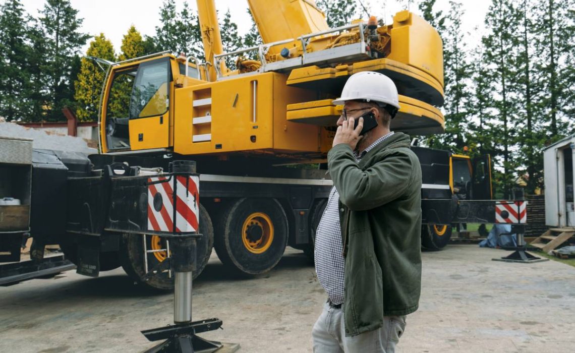 Foreman talking by phone on construction site. architect discussing project using smart phone, construction engineers planning building. Communication and safety. Man from the back (Foreman talking by phone on construction site. architect discussing p
