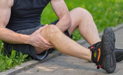 Male athlete runner touching foot in pain due to sprained ankle.