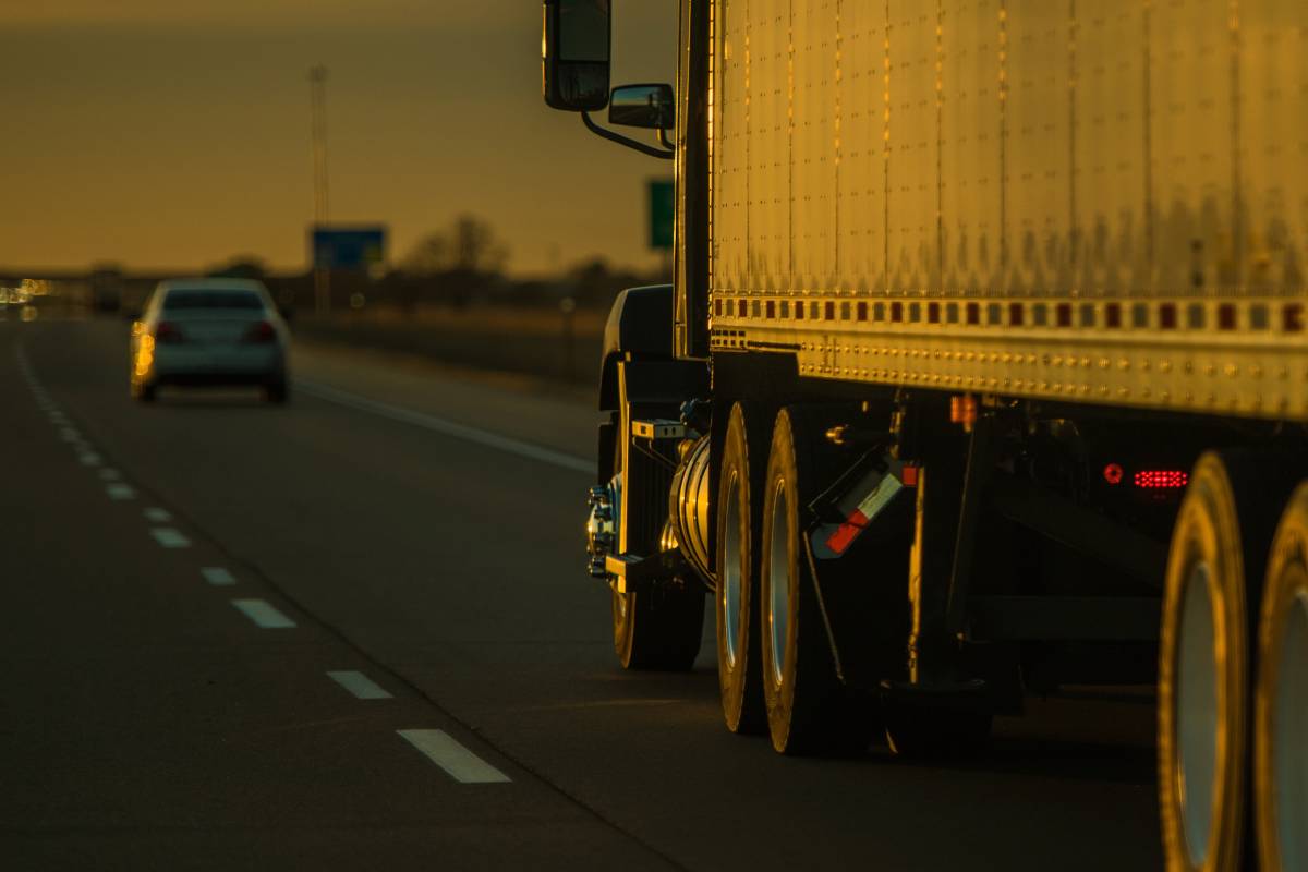 American Heavy Duty Semi Truck on the Road Illuminated with Sunset Light. Blurred Background with Copy Space on the Left. Transportation Concept.