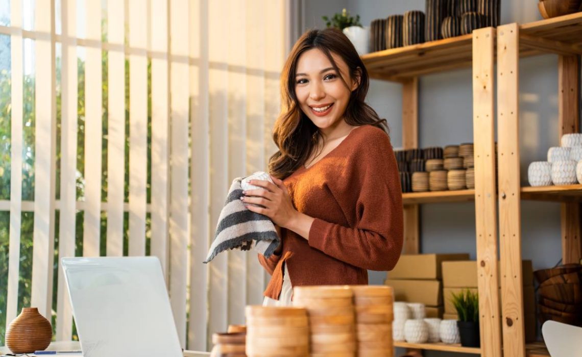 Portrait of Asian young woman pack order into box and look at camera. Beautiful attractive business girl work to preparing parcel boxes checking ecommerce shipping online retail to sell at home store.