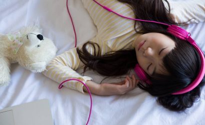 Girl listening to music while sleeping on bed