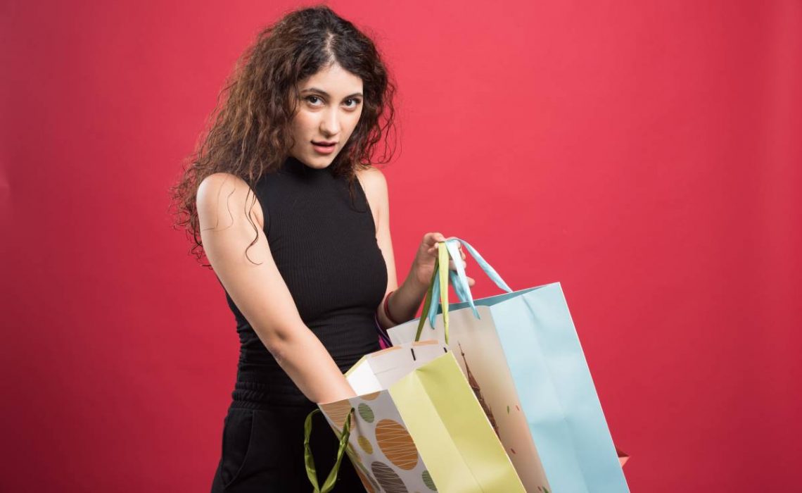 Woman showing her purchases on red background
